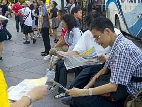 大陆游客们接过法轮功真相材料，并当场阅读起来