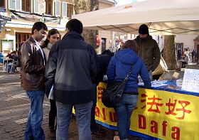 信息台前，学员在给一对外国游客讲法轮功真相。