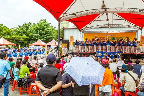 主持人感谢法轮功学员在这酷暑天气下仍然盛装表演这么清新、好听的音乐。