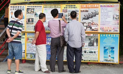 在西子湾“法轮大法好”的真相墙前，一位大陆游客正用平板电脑快照存档带回去给亲朋好友看。