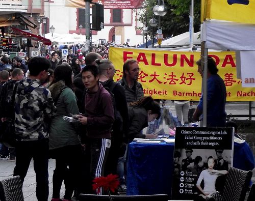 '图2：法轮功的展台前人流穿梭不息，他们拿走资料，在反迫害的表上签名'