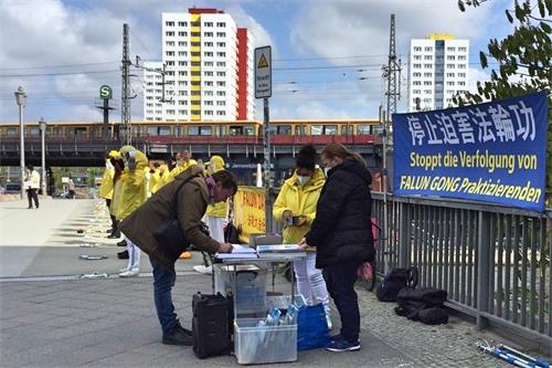 '图2：二零二一年四月二十三日，路过的民众得知中共活摘法轮功学员器官的罪行后，在学员的请愿书上签字，谴责中共暴行。'